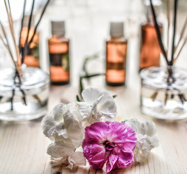 white pink Flowers in front of scented bottles