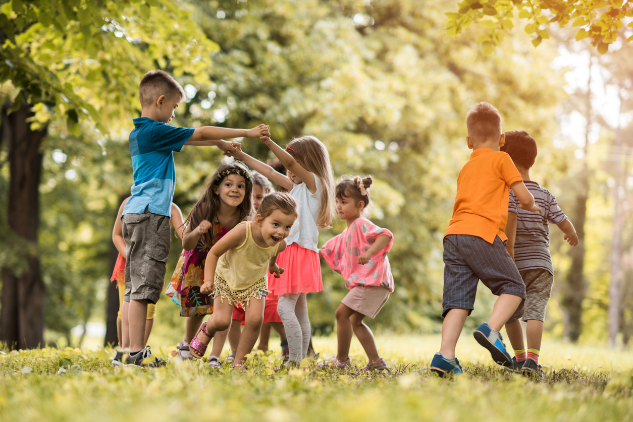 Gruppe von Kindern spielt gemeinsam im Grünen auf einer Wiese.
