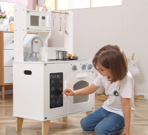 Kind spielt mit weisser Kinderküche aus Holz mit Tafel zum Bemalen | Quelle: supermami.ch